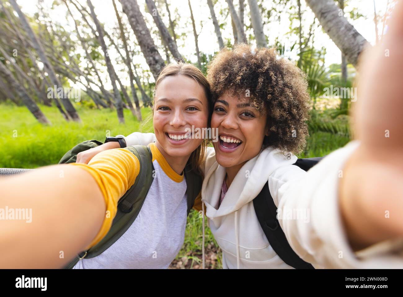 Zwei Frauen machen ein Selfie auf einer Wanderung, eine mit blondem Haar und die andere mit lockigem Haar Stockfoto