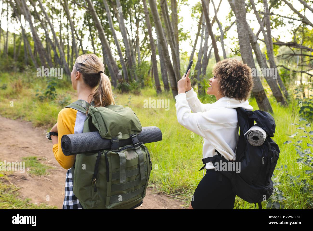 Junge Kaukasierin und Frau mit birassischer Herkunft erkunden einen Waldweg auf einer Wanderung Stockfoto