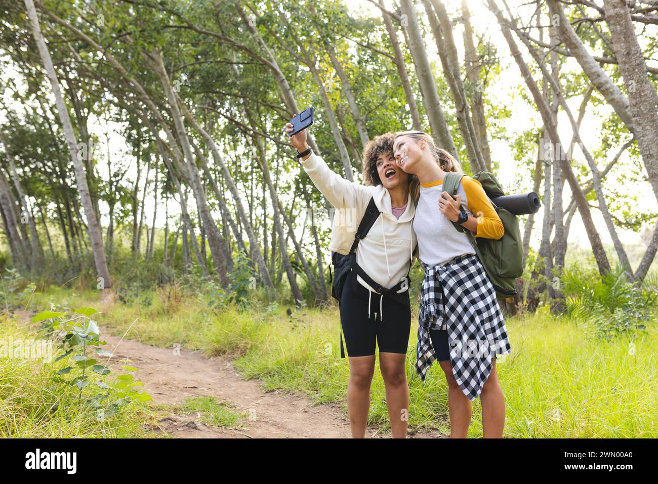 Junge kaukasische Frau und birassische Frau machen ein Selfie im Wald auf einer Wanderung mit Kopierraum Stockfoto