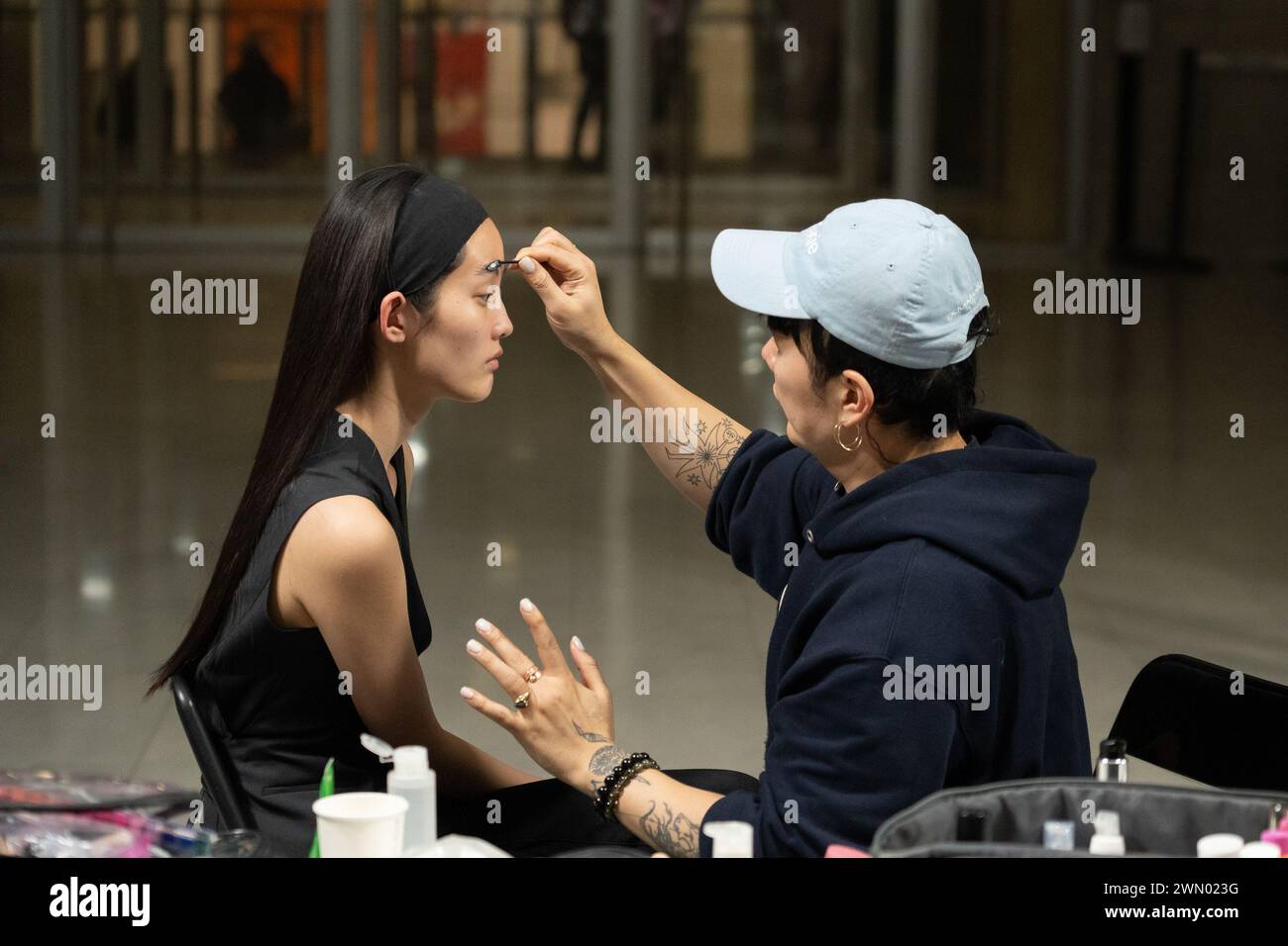 Mailand, Italien. Februar 2024. Ein Make-up-Künstler verleiht einem Model vor der Maison Yoshiki Paris Fashion Show den letzten Schliff. Backstage-Vorbereitung für die Maison Yoshiki Paris Fashion Show während der Maison Fashion Week Damen Herbst/Winter 2024-2025 an der Mailänder Bocconi Universität (Foto: Paolo Marelli/SOPA Images/SIPA USA) Credit: SIPA USA/Alamy Live News Stockfoto