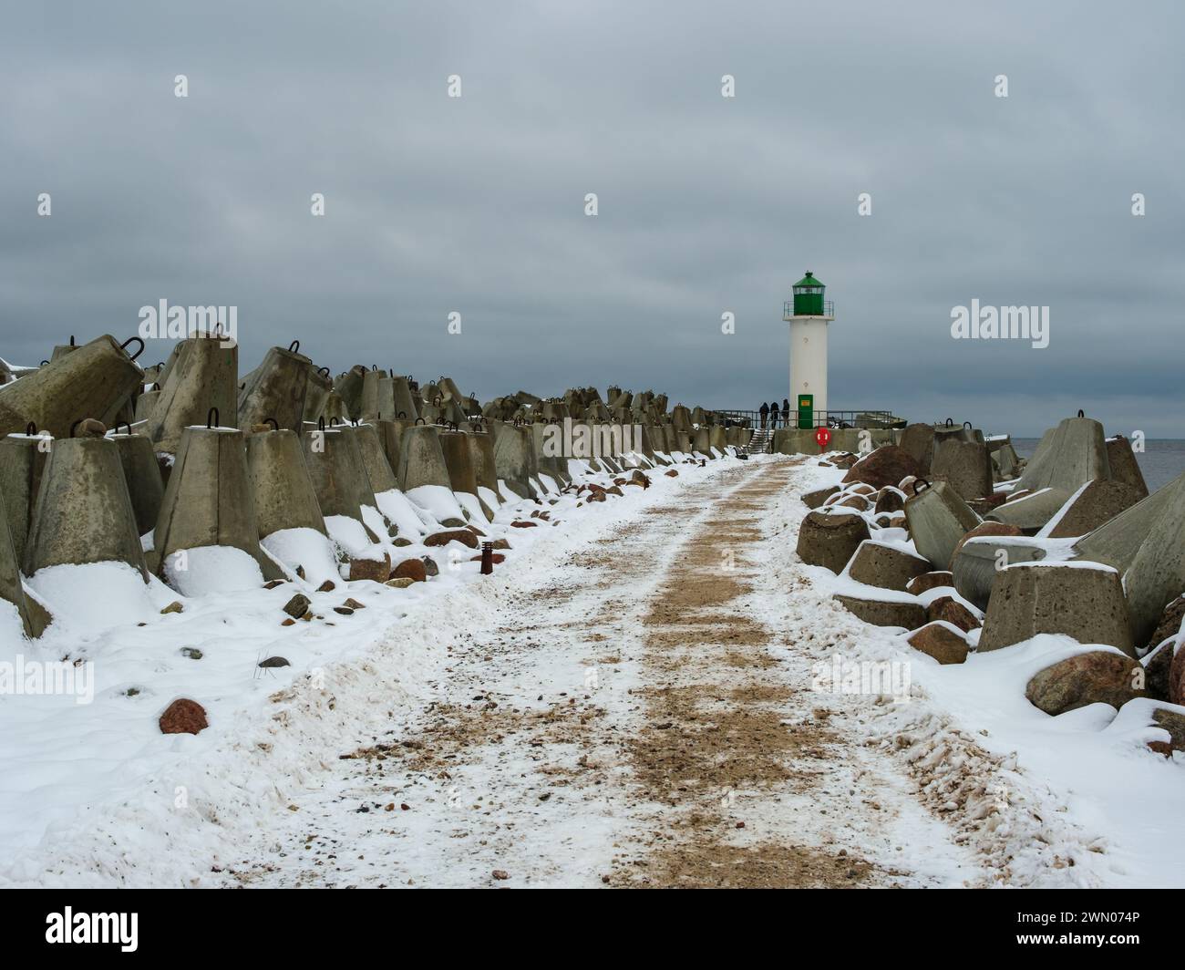 Unter einer Schneedecke mündet der Pfad in Richtung Ventspils Southern Pier und Lighthouse, wo Sie einen ruhigen Einblick in die maritime Geschichte im W erhalten Stockfoto