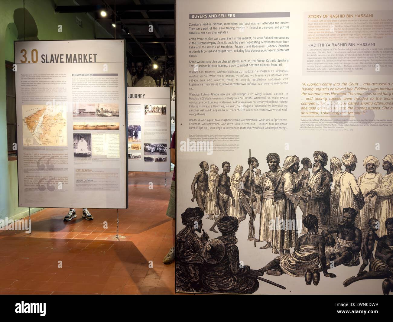Eine westliche Touristin sieht sich eine Ausstellung in der Ostafrikanischen Sklavenhandelsausstellung in Stone Town, Sansibar, Tansania an Stockfoto