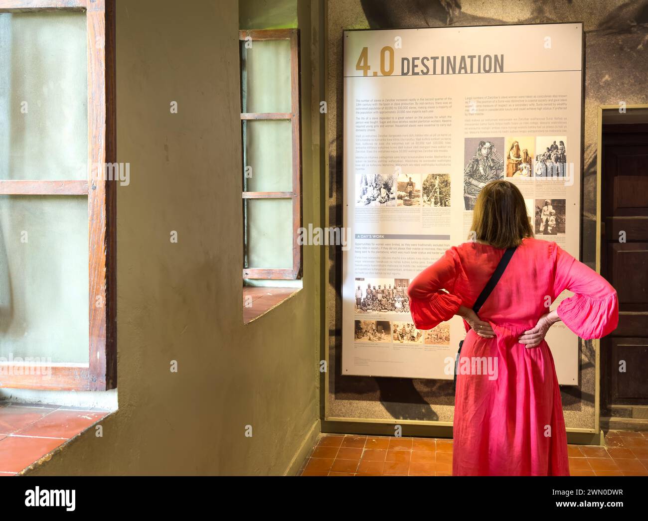 Eine westliche Touristin sieht sich eine Ausstellung in der Ostafrikanischen Sklavenhandelsausstellung in Stone Town, Sansibar, Tansania an Stockfoto