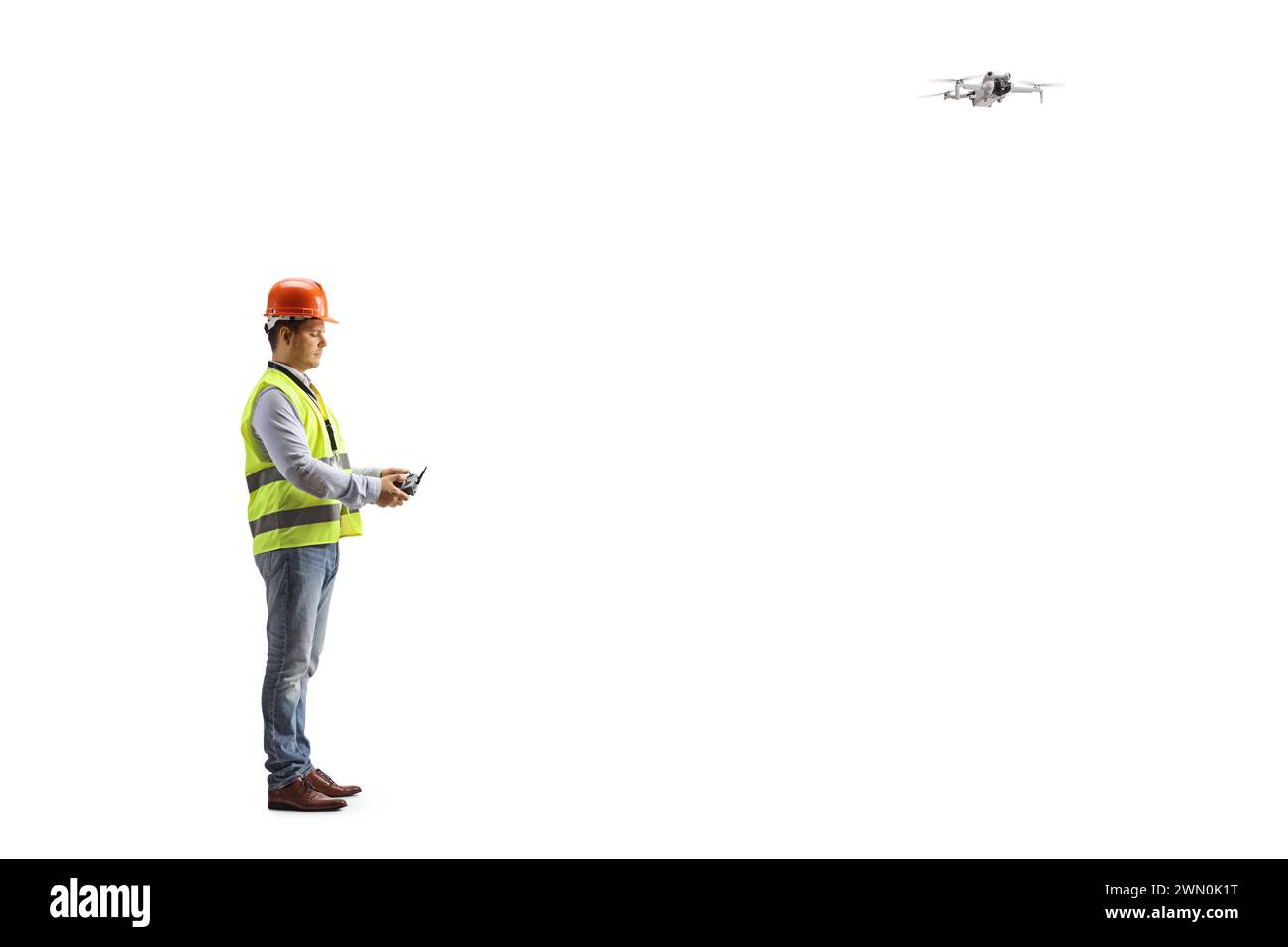 Ingenieur in einer Sicherheitsweste, die eine Drohne isoliert auf weißem Hintergrund fliegt Stockfoto