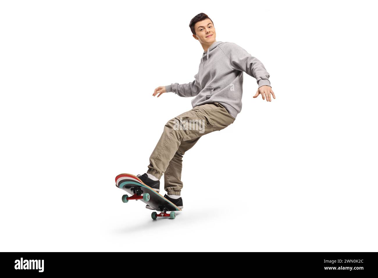 Glücklicher Kerl, der auf einem Skateboard auf weißem Hintergrund fährt Stockfoto