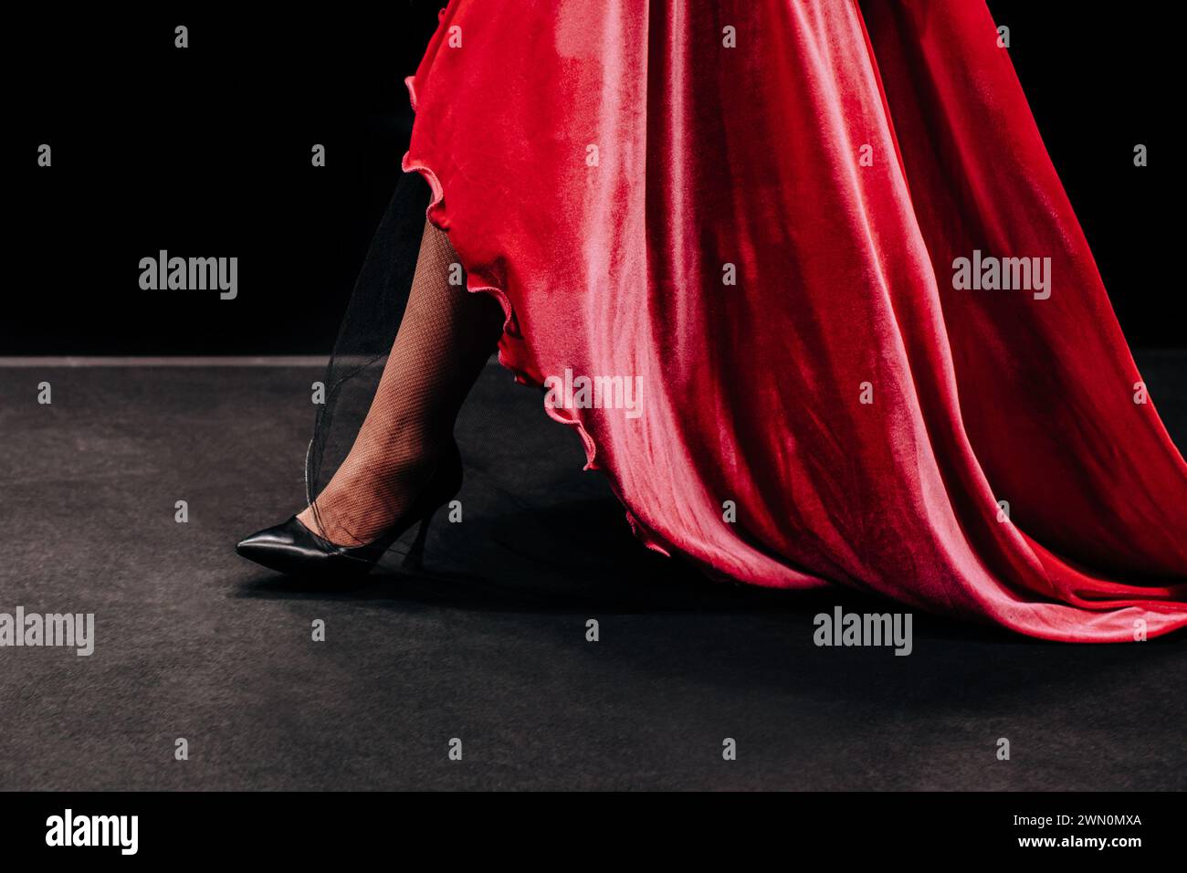 Details eines roten Samtkleides mit langem Saum. Damenbekleidung elegantes Outfit. Seitenansicht Stockfoto