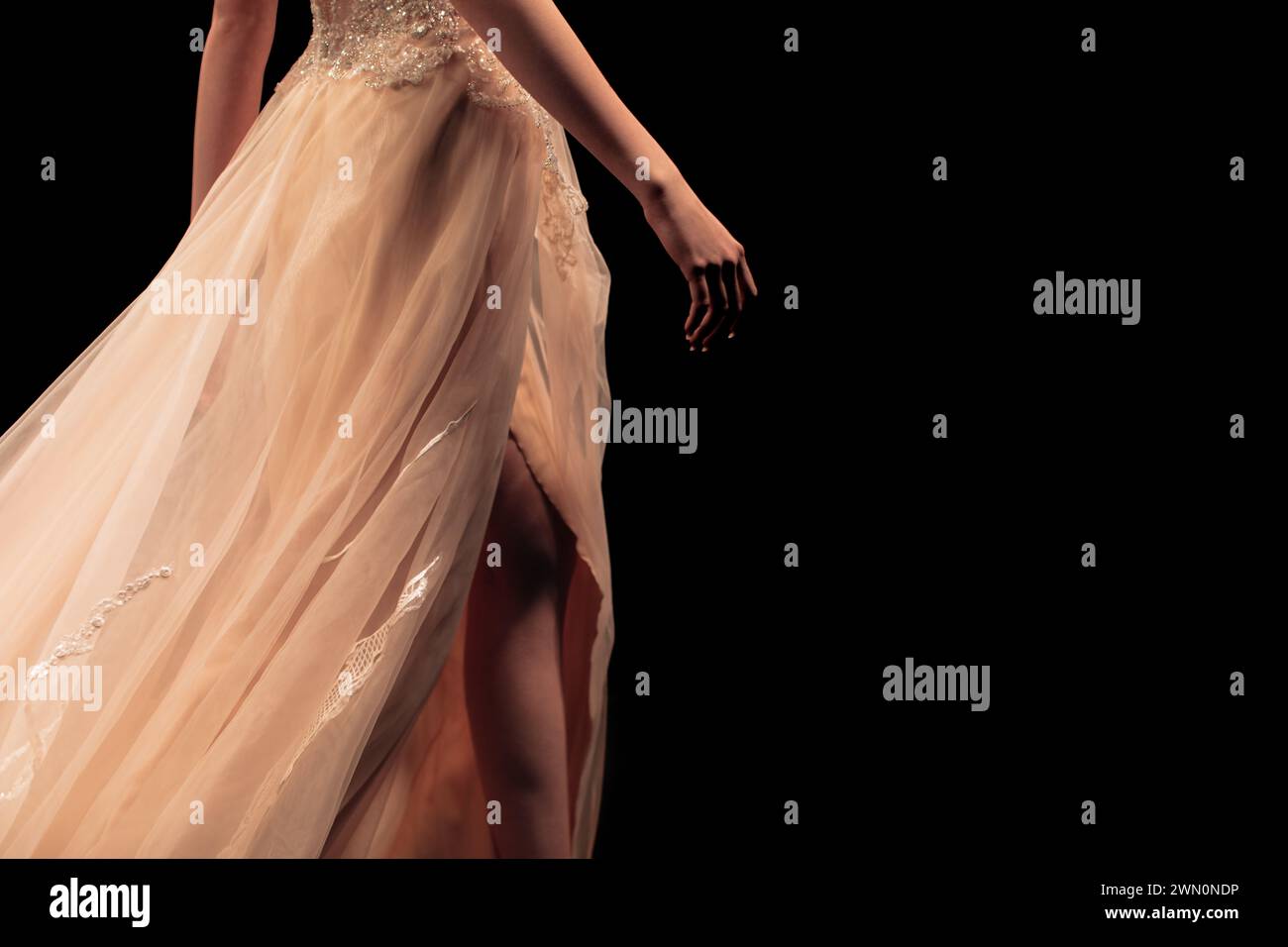 Beigefarbenes schickes Abendkleid auf einer weiblichen Figur auf schwarzem Hintergrund. Feminine Mode elegante Kleidung Stockfoto