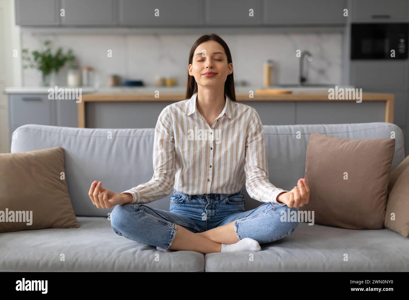 Frau, die zu Hause auf der Couch Meditation übt Stockfoto