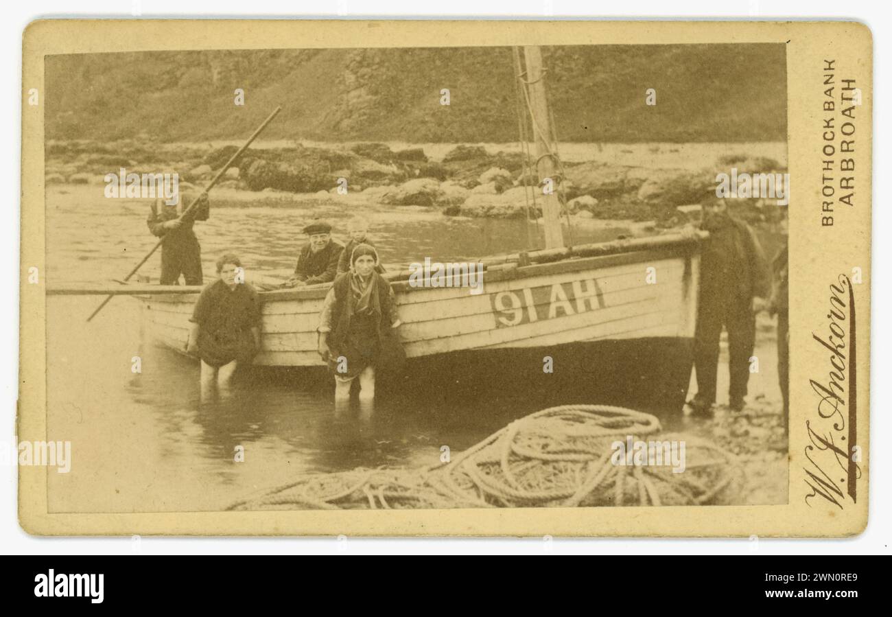 Originale viktorianische Carte de Visite (Visitenkarte oder CDV) mit traditionellen schottischen Fischern, Fischfrauen, Familie, die ein Fischerboot (registriert als 91 AH) in Auchmithie, nahe Arbroath, Angus, Schottland startet. Arbroath ist berühmt für den berühmten Arbroath Smokie - geräucherter Schellfisch, kleinere Boote wie diese wurden zum Angeln von Krabben und Hummer verwendet. Von dem schottischen Fotografen W J Anckorn aus Arbroath (Studios an der Brothock Bridge und der Brothock Bank), Schottland, Großbritannien um 1880 Stockfoto