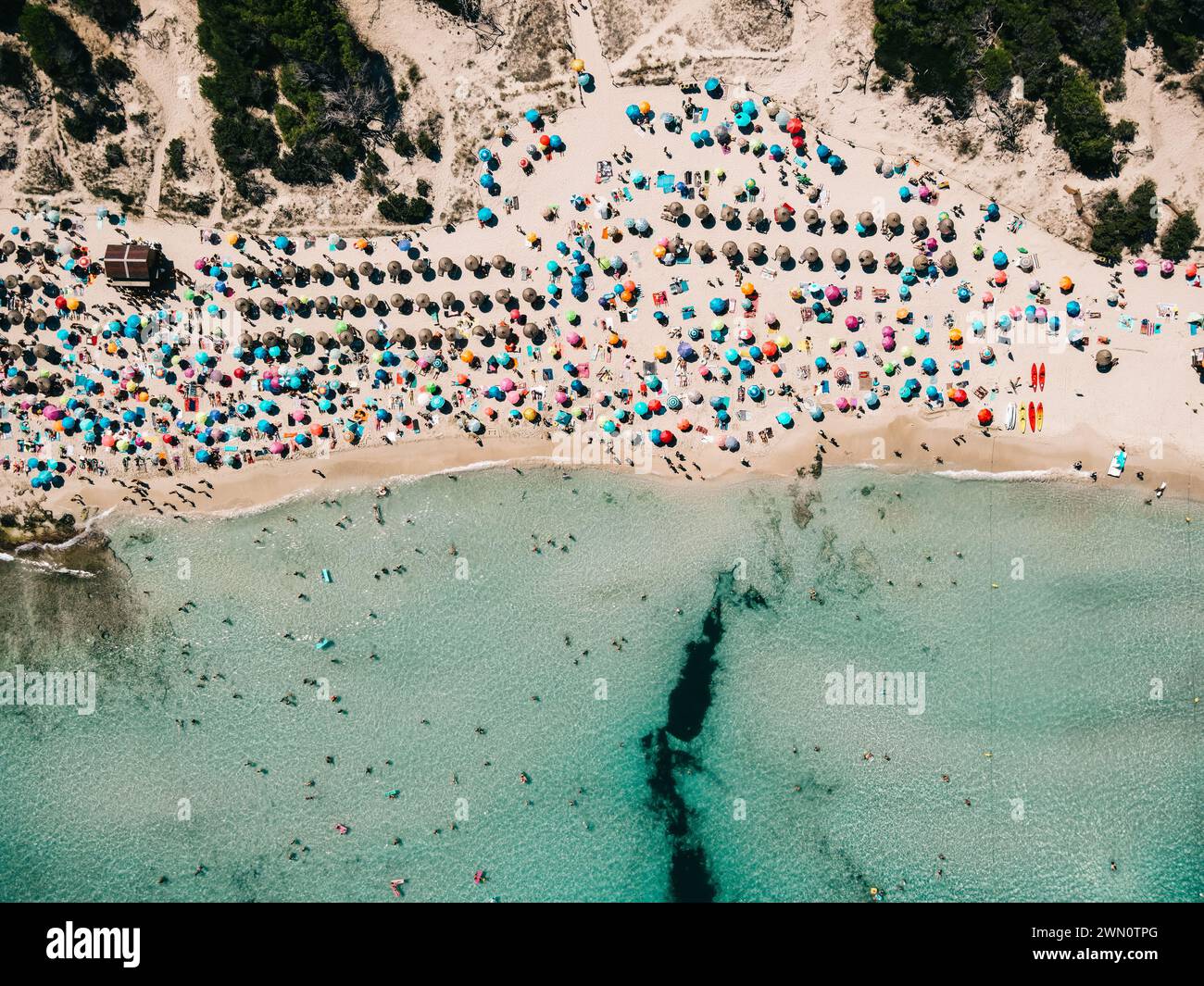 Aus der Vogelperspektive auf den Sandstrand mit bunten Sonnenschirmen, unerkennbare Menschen, die Küste mit transparentem blauem Wasser an sonnigen Tagen im Sommer. Reisen Sie in Mal Stockfoto