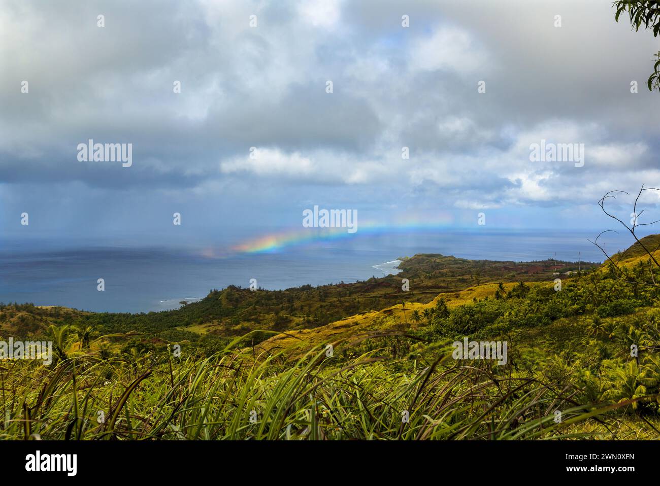 Ein Regenbogen über der Westküste Guams mit zeitweiligen Regenböen. Stockfoto