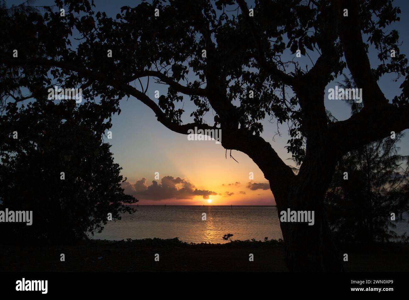 Der Sonnenuntergang durch Silhouetten im Nimitz Beach Park in Agat, Guam Stockfoto