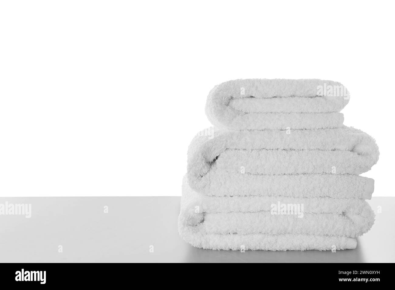 Frische Handtücher auf hellgrauem Tisch vor weißem Hintergrund. Platz für Text Stockfoto
