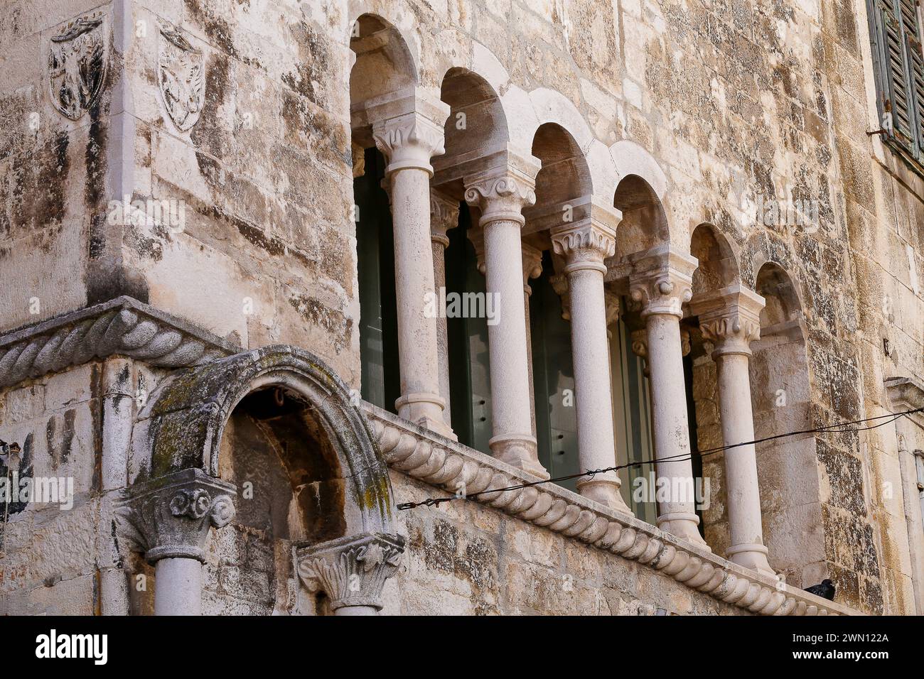 Straßenblick auf die oberen Stockwerke von mittelalterlichen Wohnhäusern aus Stein in der engen Gasse in der Altstadt von Split, Kroatien. Stockfoto