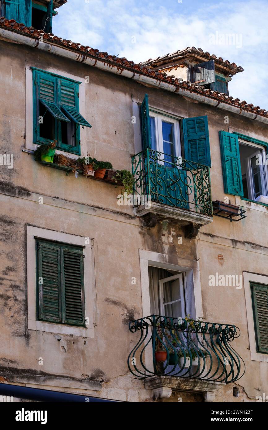 Blick auf die oberen Stockwerke mittelalterlicher Wohnhäuser aus Stein, mit malerischen Fensterläden und Blumenkästen, in einer engen Gasse Stockfoto