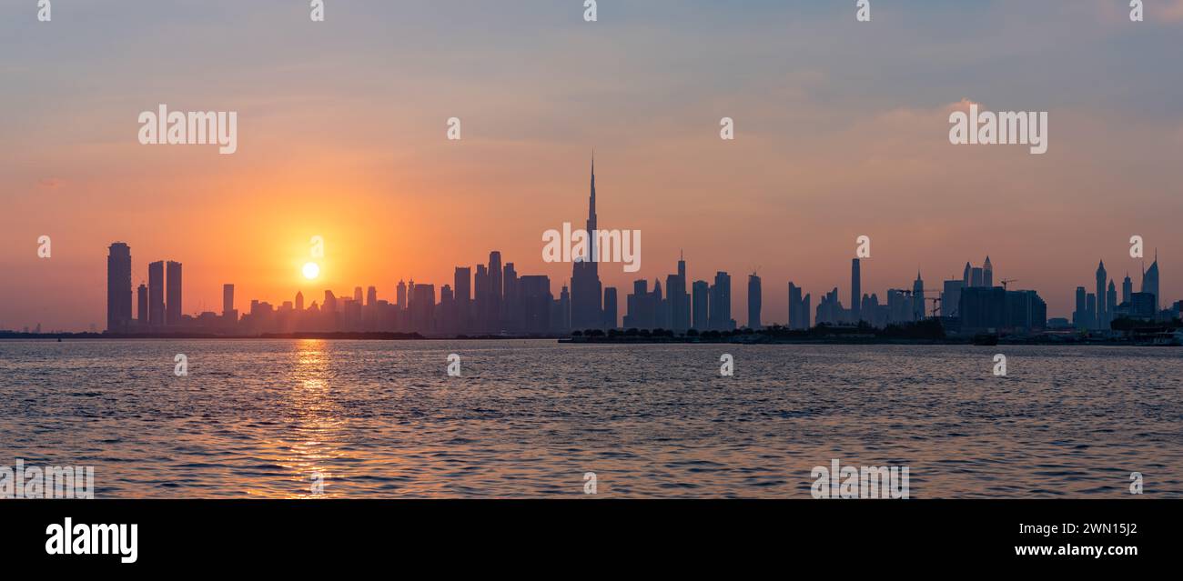 Ein Panorama und ein farbenfrohes Bild der Innenstadt von Dubai bei Sonnenuntergang mit dem Burj Khalifa, der alle Hochhäuser überragt. Stockfoto