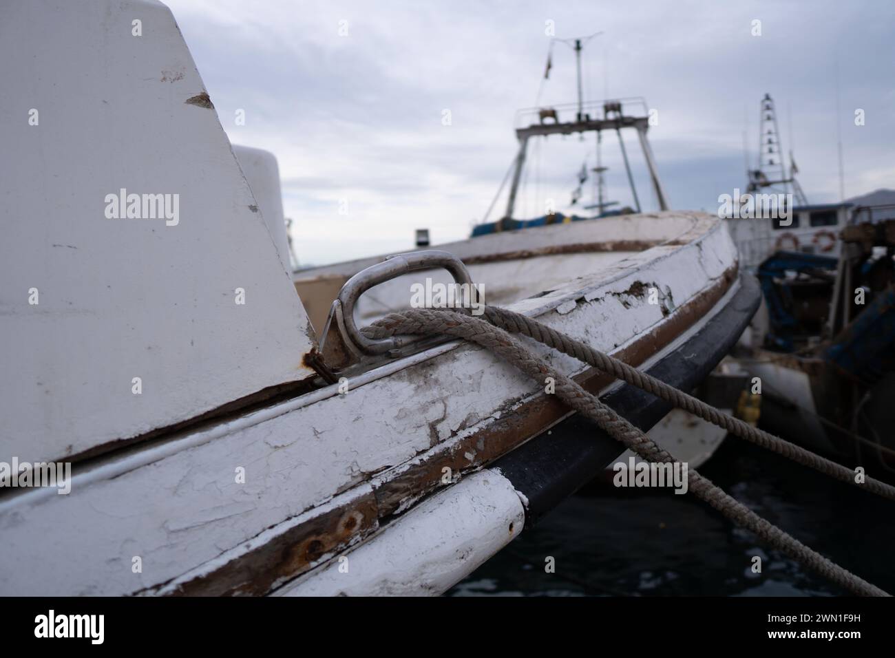 Ein Boot, das in der Nähe von Menschen an einem Dock am Wasser verankert ist Stockfoto