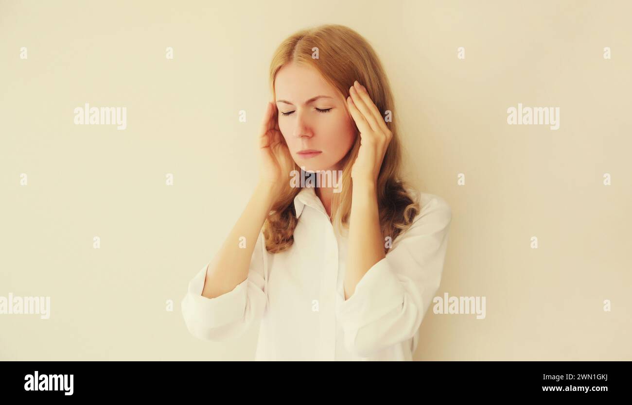 Erschöpfte, müde weiße junge Frau Angestellte mit Kopfschmerzen oder Schläfenschmerzen, leidet an Migräne, Kopfverspannungen zu Hause oder im Büro Stockfoto