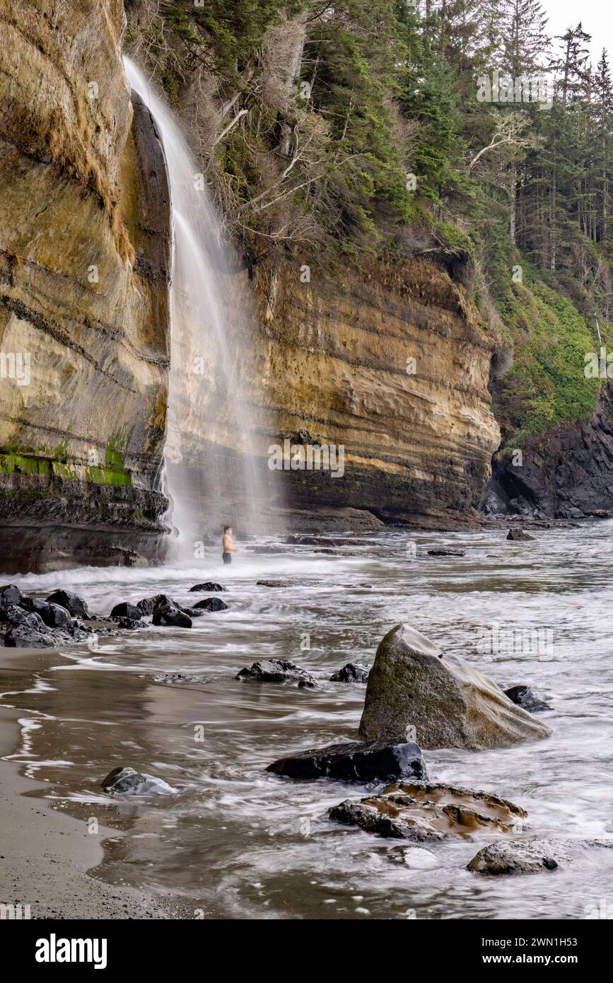 Person, die im kalten Wasser der Mystic Beach Falls steht - in der Nähe von Sooke, Vancouver Island, British Columbia, Kanada Stockfoto