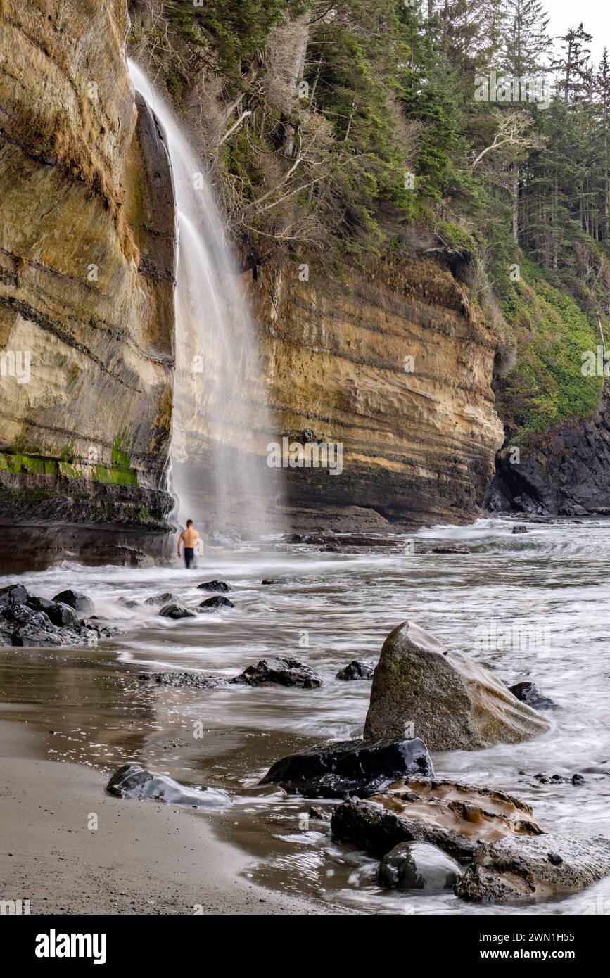 Person, die im kalten Wasser der Mystic Beach Falls steht - in der Nähe von Sooke, Vancouver Island, British Columbia, Kanada Stockfoto