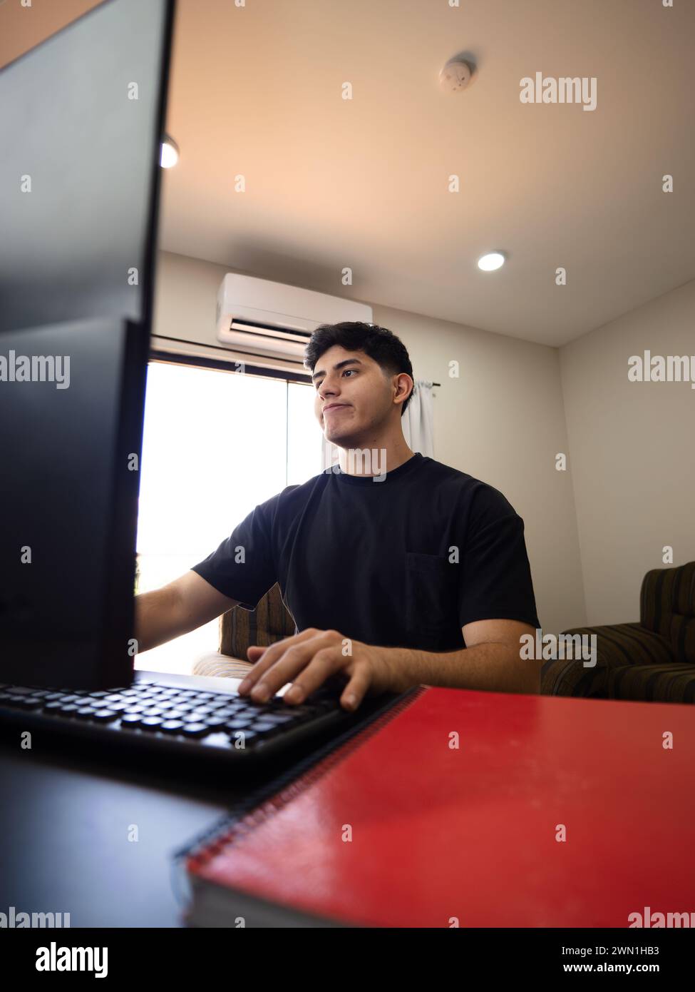 Ein junger Mann, der von zu Hause aus arbeitet oder studiert, zeigt einen Ausdruck von Resignation und Ärger Stockfoto