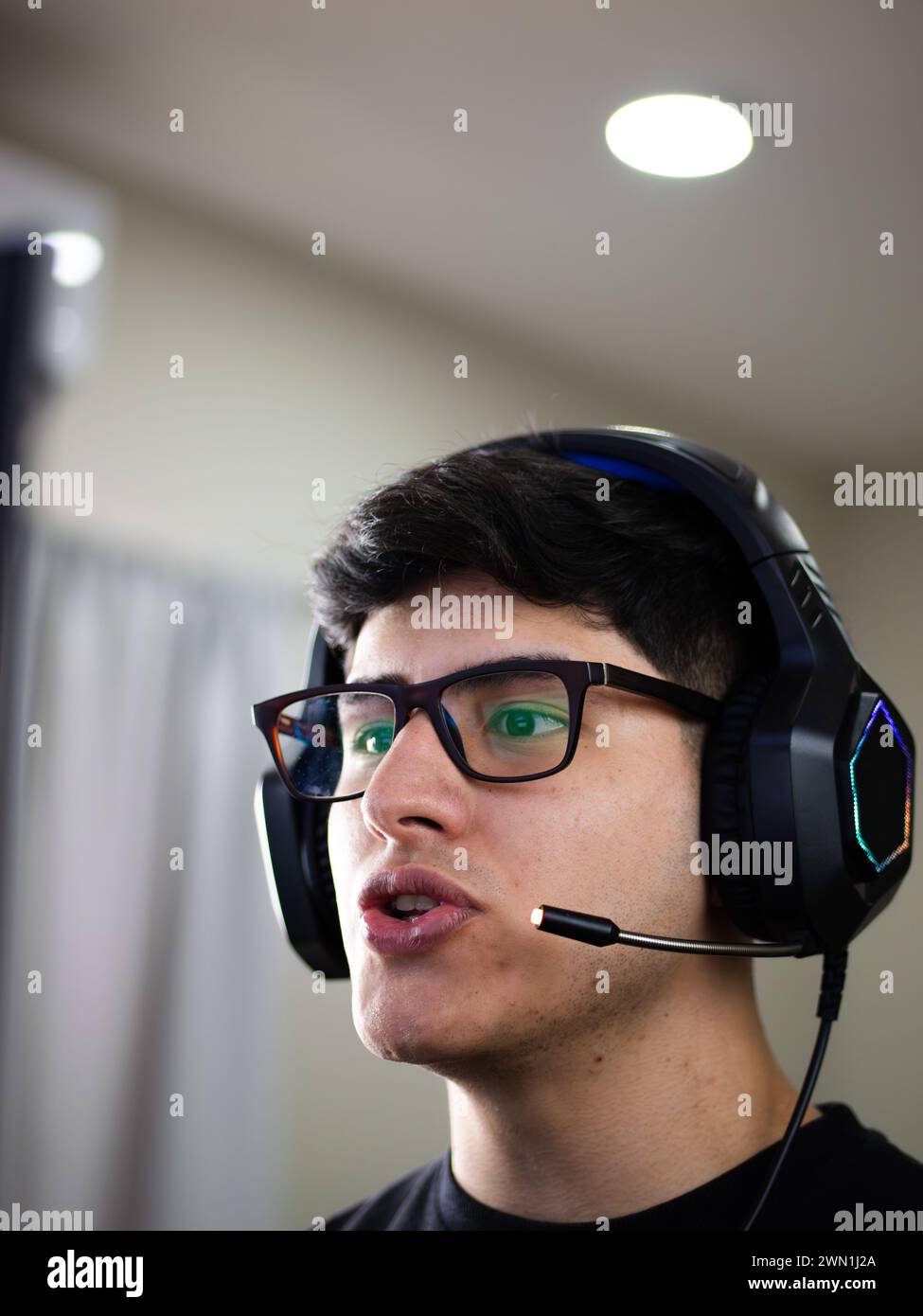 Ein gutaussehender junger Mann aus Kaukasien, der Brille und Kopfhörer trägt, hält einen Live-Talk, entweder indem er einen Kurs anbietet oder an einem Online-Studium teilnimmt Stockfoto