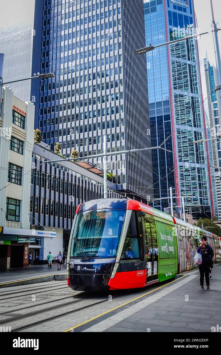 Ein Sydney Light Rail-Zug fährt an einem sonnigen Tag aus einer Station in der George Street in Sydney heraus und erfasst die urbane Szene und die Verkehrsaktivitäten in Stockfoto
