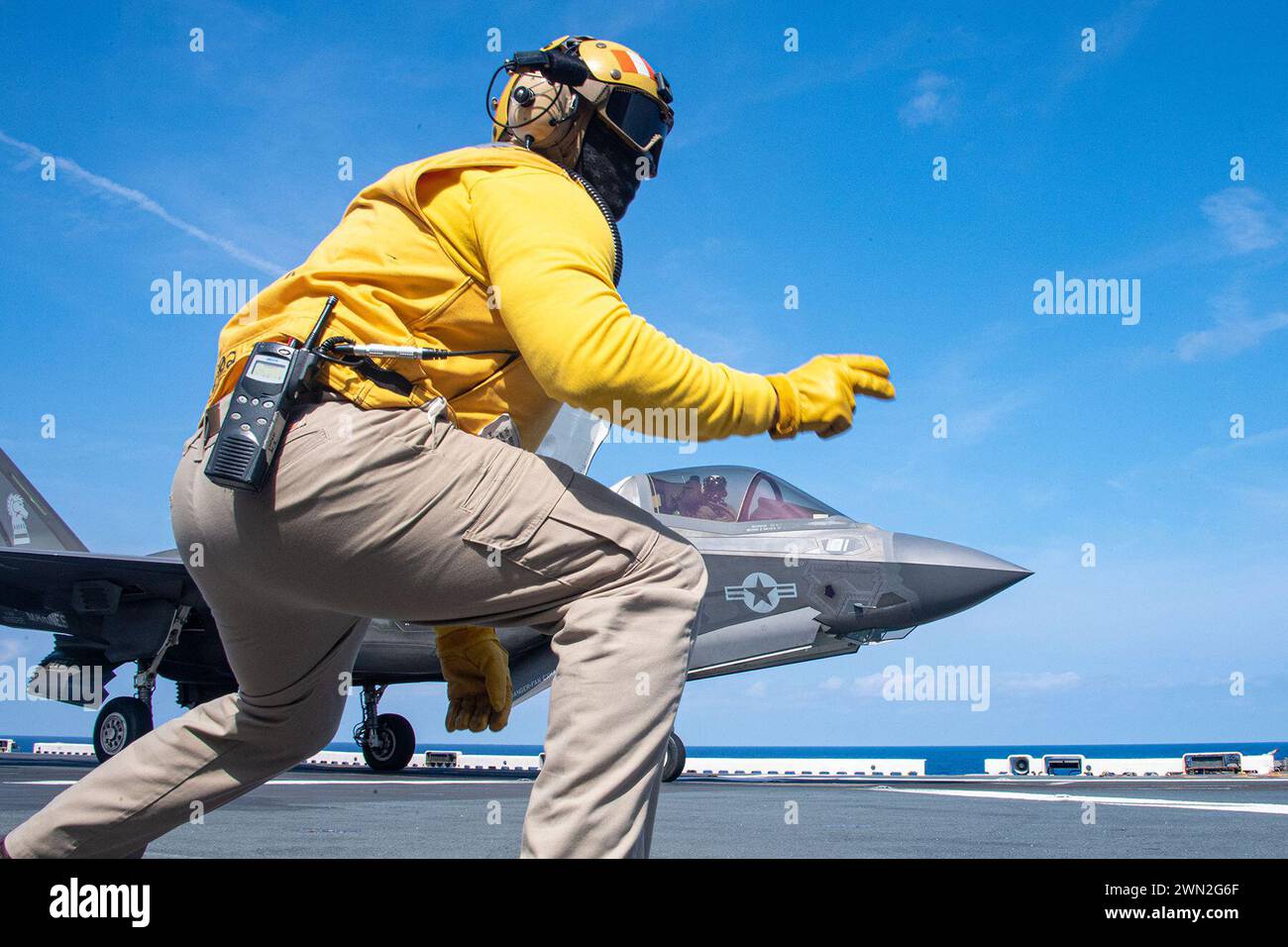 Pazifik. Februar 2024. Chief Aviation Boatswains Mate (Handling) Jeff Acevedo aus San Diego, der dem vorwärtsgerichteten amphibischen Angriffsträger USS America (LHA 6) zugeteilt wurde, signalisiert ein F-35B Lightning II Flugzeug vom 31st Marine Expeditionary Unit'ss (MEU) Air Combat Element (ACE), das während der Durchführung von Flugoperationen im Pazifik im Februar 18 startet. America, Leitschiff der America Amphibious Ready Group, ist im Einsatzgebiet der 7. US-Flotte im Einsatz. Die 7. US-Flotte ist die größte nach vorne ausgerichtete nummerierte Flotte der US-Navys und interagiert routinemäßig Stockfoto