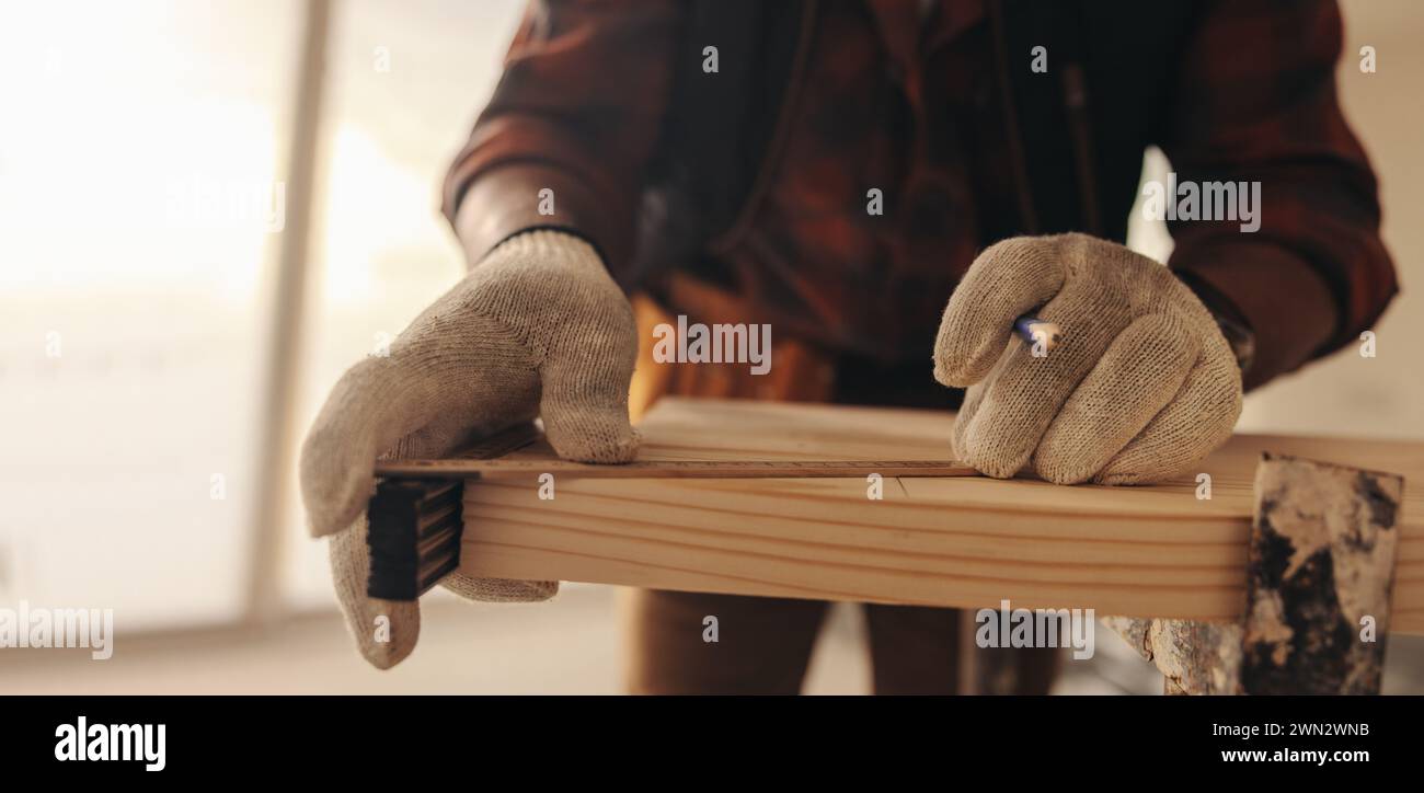Hausbesitzer misst und markiert Holz für die Renovierung eines Wohnraums. Mit akribischer Liebe zum Detail zeigt der Umbau der Zimmerei das Können des Mannes Stockfoto