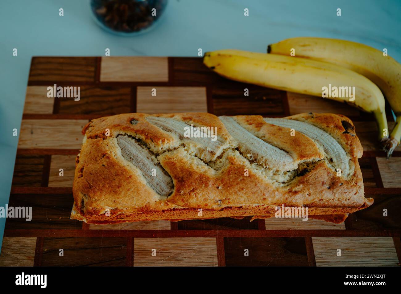 Natürliches Licht hebt ein Bananenbrot und eine frische Banane auf der Küchenoberfläche hervor Stockfoto