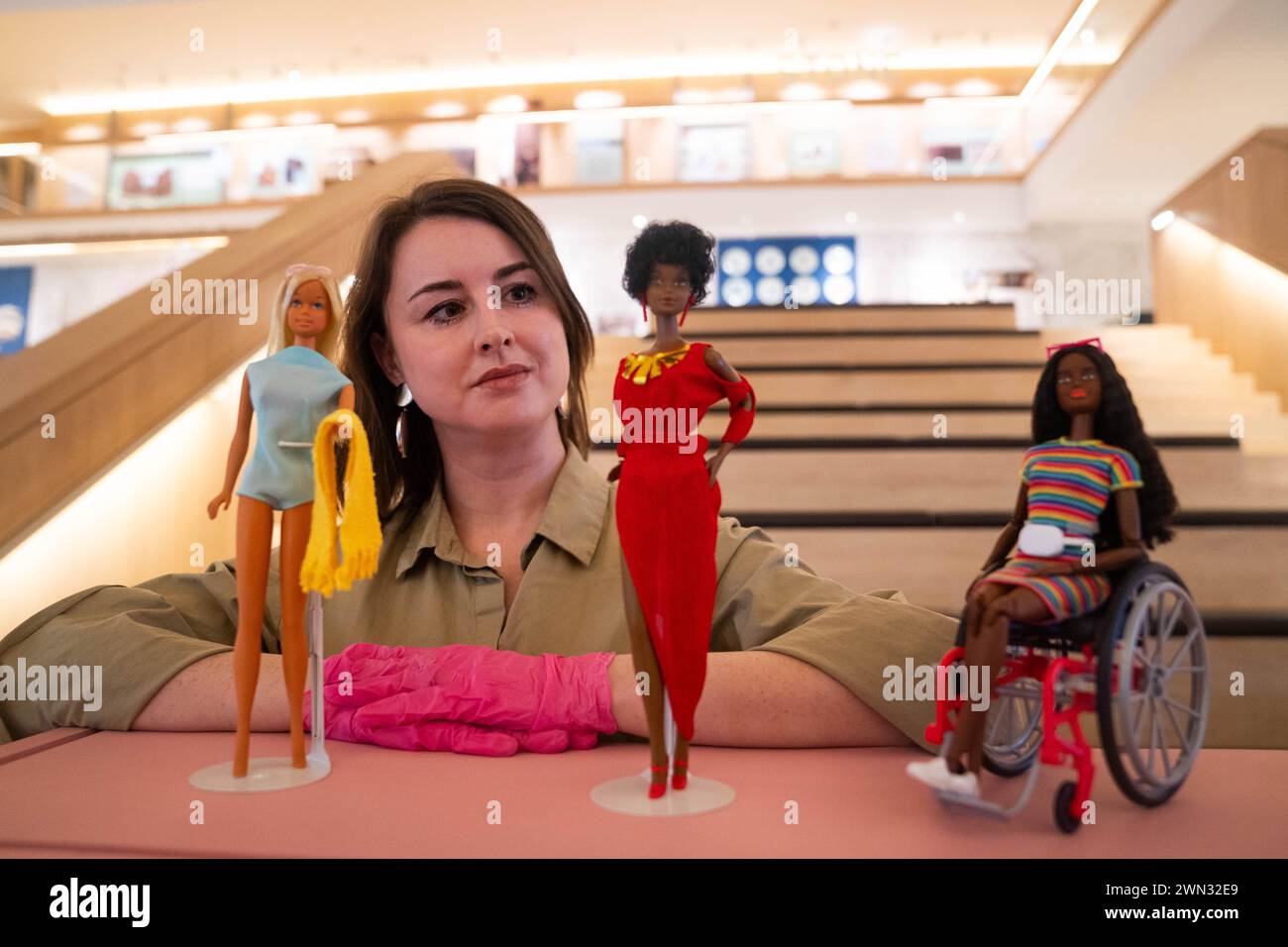 Die Ausstellungskuratorin Danielle Thom steht unter Barbie Puppen, bevor sie die Puppen, Kleider und Traumhäuser ankündigt, die im Design Museum for Barbie: The Exhibition zu sehen sind. Bilddatum: Donnerstag, 29. Februar 2024. Stockfoto