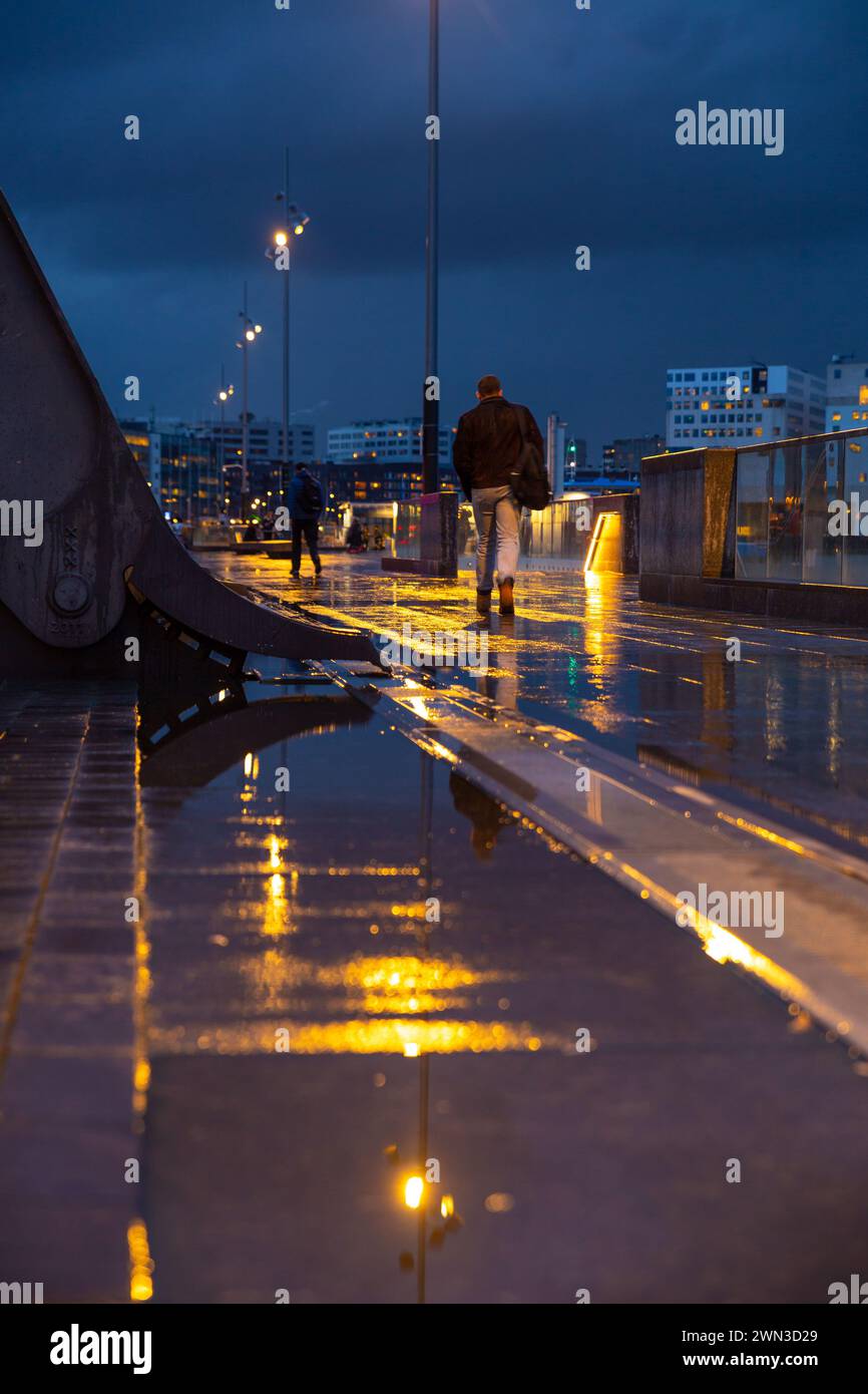 Nasse Straße im Amsterdamer Hauptbahnhof mit Wasserspiegelung auf der Straße Stockfoto