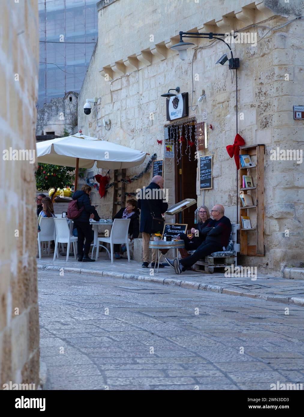 Matera, Italien – 30. Dezember 2023: Touristen genießen Winterurlaub in einem Café/einer Höhlenbar im Freien Stockfoto