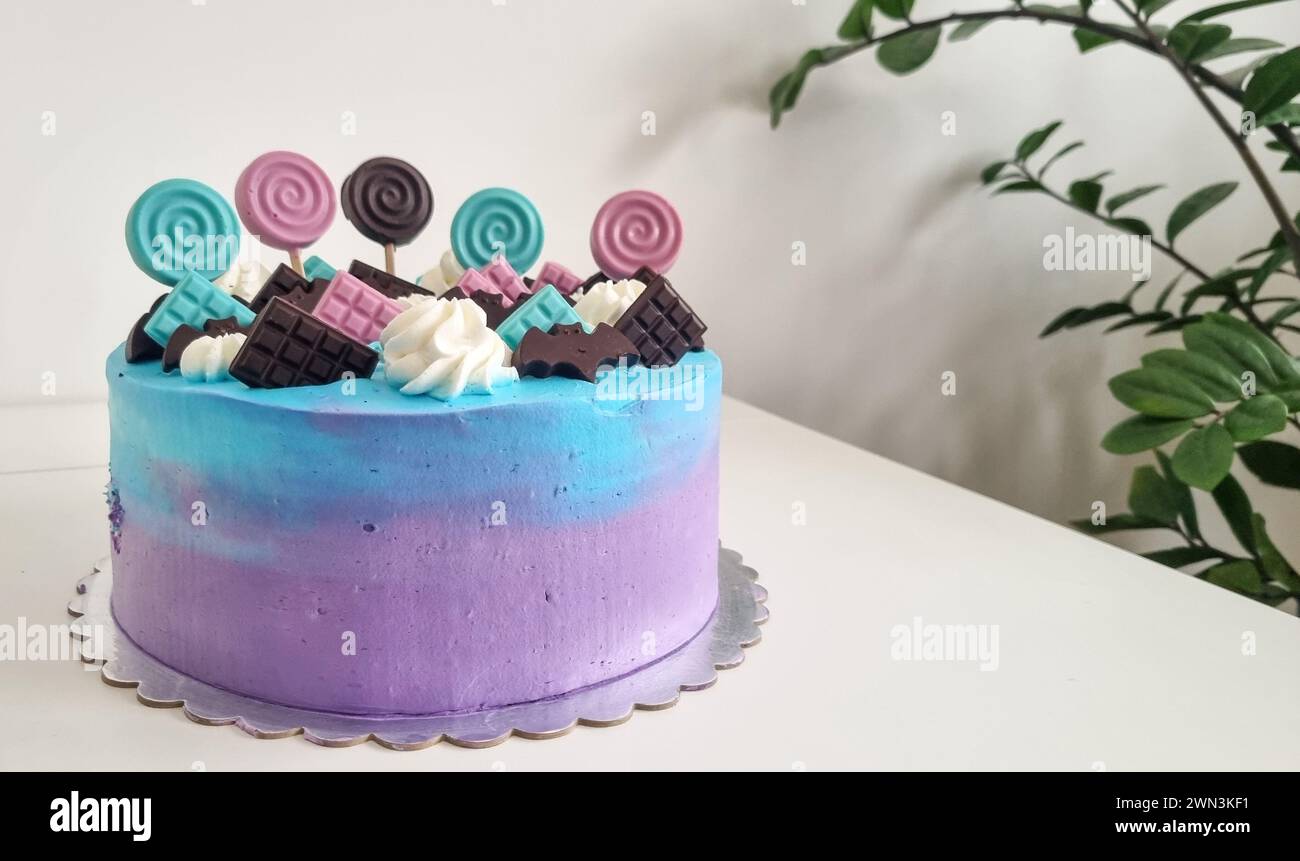 Ein farbenfroher Ombre-Kuchen mit Süßigkeiten auf einem weißen Tisch Stockfoto