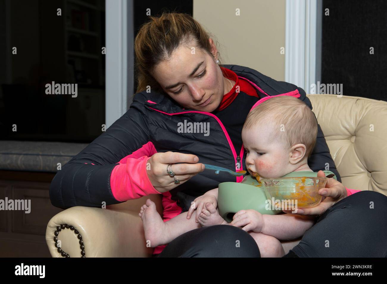 Mutter füttert einen 4 Monate alten Jungen mit einem Löffel. Stockfoto
