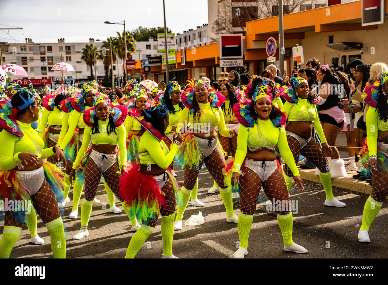 Straßenkünstler in gelben und rosa Kostümen tanzen mit anderen auf der Straße Stockfoto