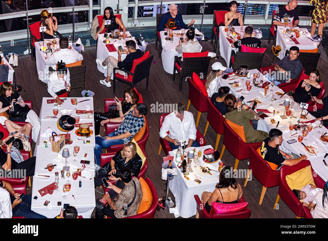 Restaurantgäste mit Mobiltelefonen bei Silvesterparty in der Red Sky Bar 56 auf dem Dach, Centara Hotel, Bangkok, Thailand Stockfoto