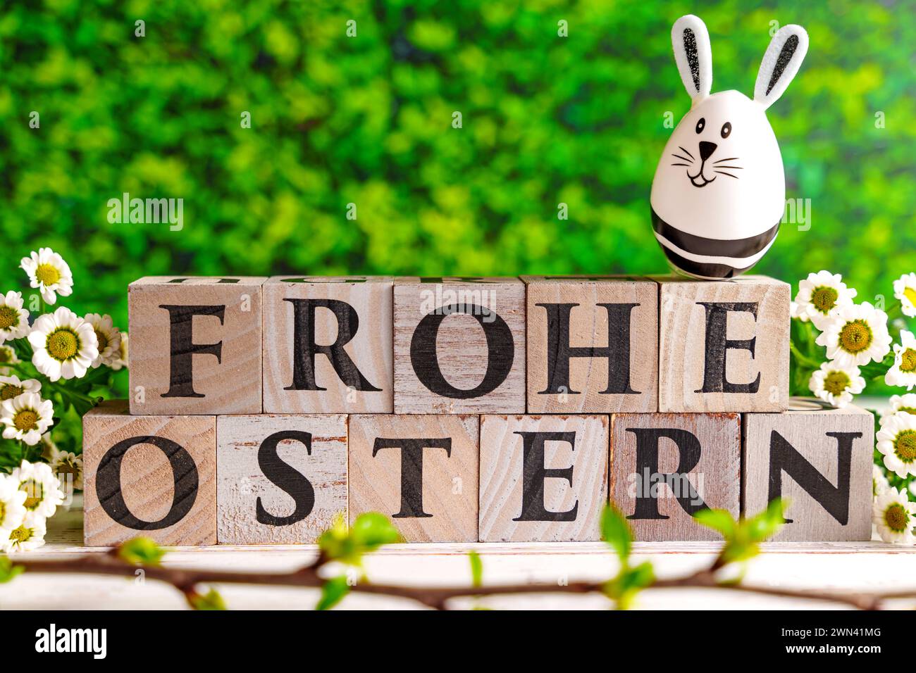Augsburg, Bayern, Deutschland - 28. Februar 2024: Happy Easter geschrieben mit Holzwürfeln, Osterhasen-Ei und Frühlingsblumen. Ostersymbolbild *** Frohe Ostern schreibt mit Holzwürfeln, Osterhasen EI und frühlings Blumen. Oster-Symbolbild Stockfoto