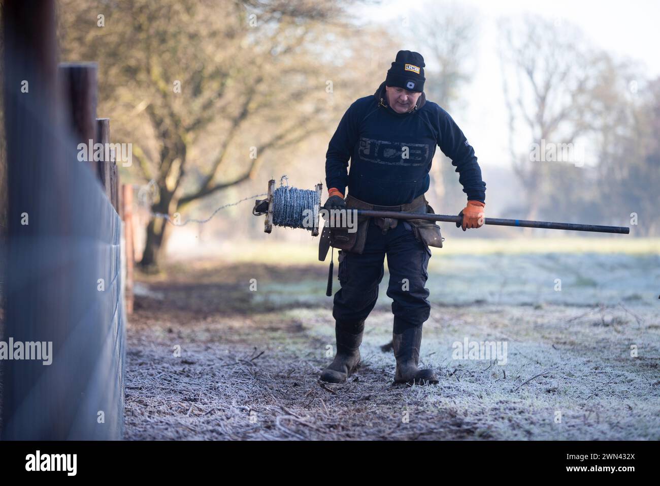 13/01/22 Ein Zaununternehmer trägt Arbeitskleidung von JCB, während er an einem frostigen Morgen im Churnet Valley, Staffordshire, einen neuen Zaun aufbaut. Alle R Stockfoto