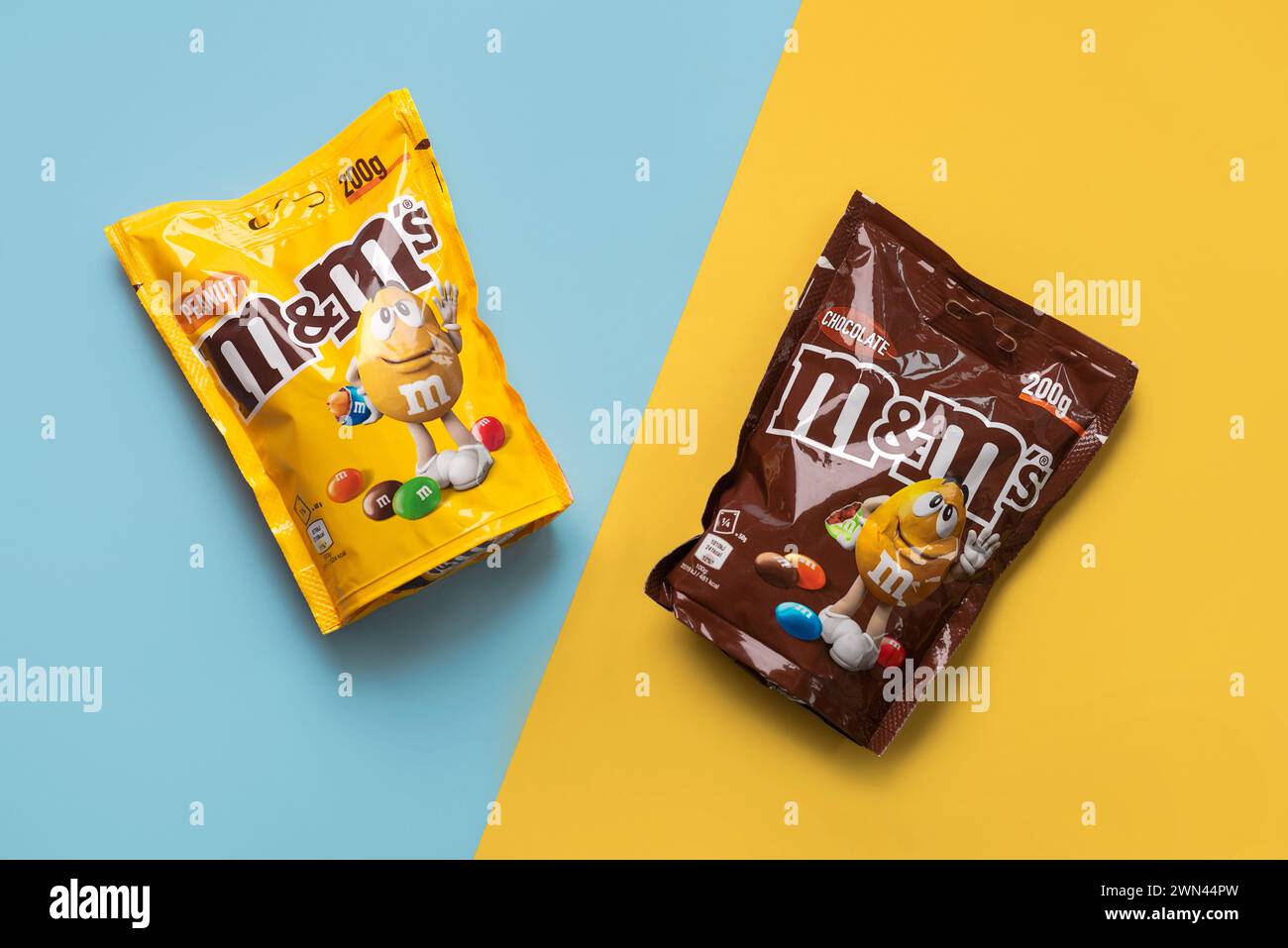 Nahaufnahme von Packungen mit Schokolade und Erdnuss auf blauem und gelbem Hintergrund. Illustrativer Leitartikel Stockfoto