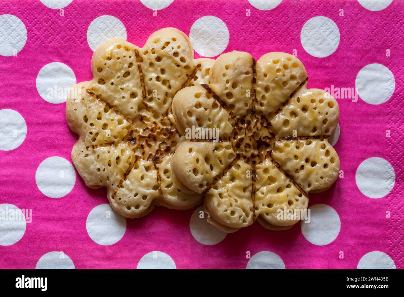 Blühende schöne Krumppern leichte flauschige, blumenförmige Krumpets von M&S auf rosa Polka Dots Serviette Stockfoto
