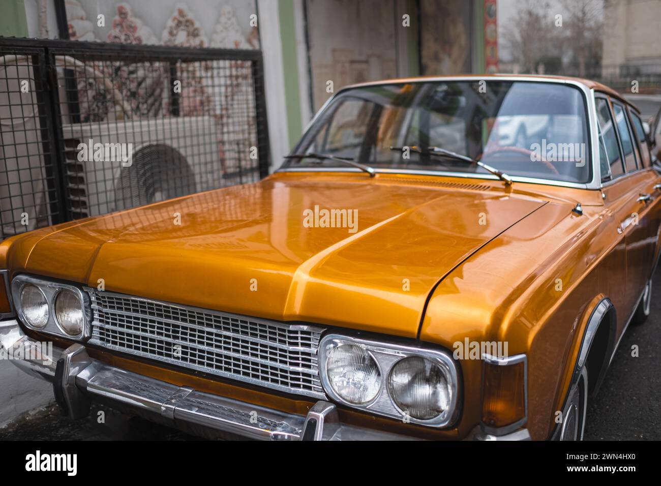 Klassischer Sportwagen, der auf einer städtischen Straße geparkt ist. Alte orange amerikanische Auto-Nahaufnahme. Muscle Car-Scheinwerfer. Straßenfoto, niemand Stockfoto