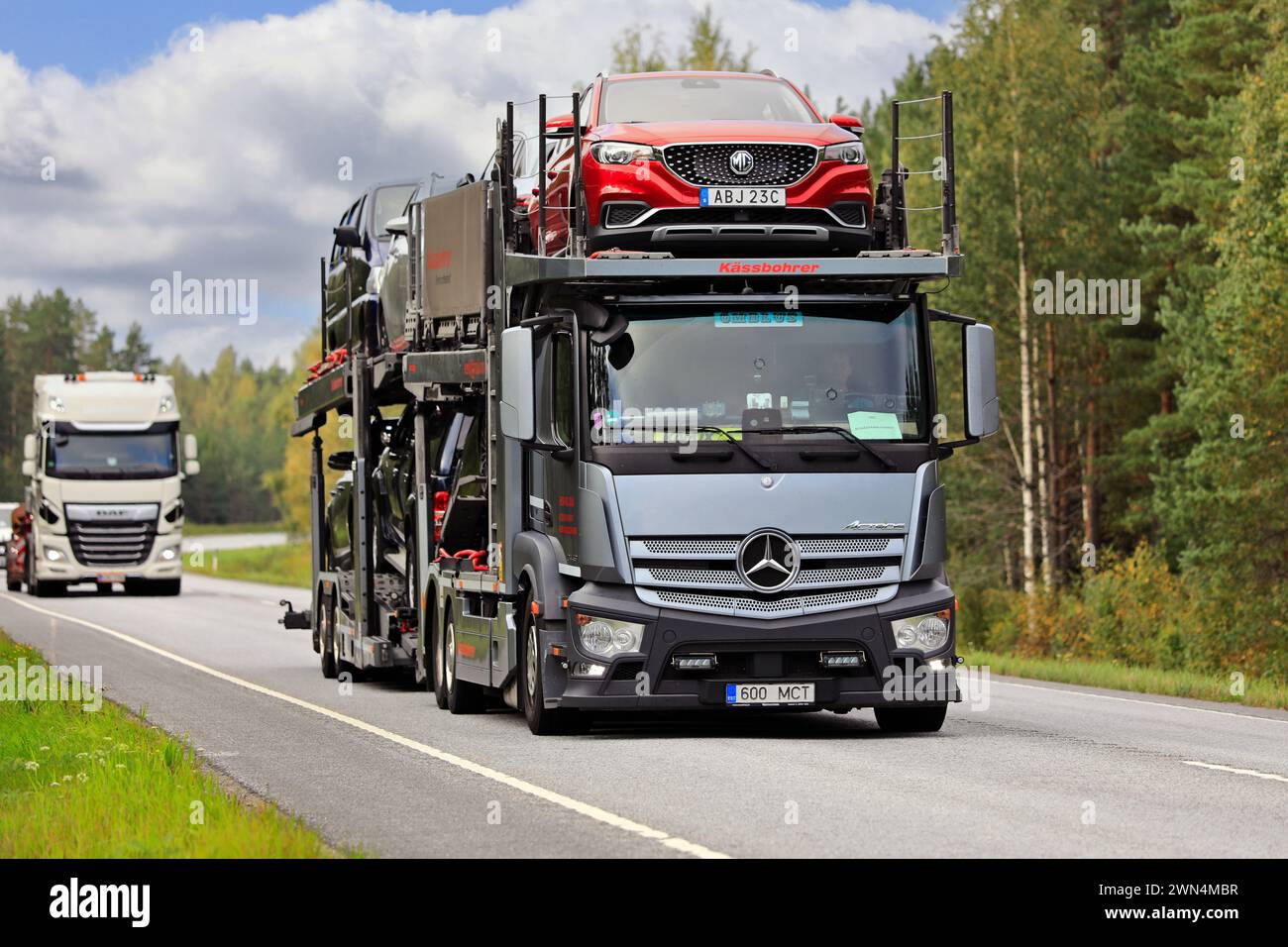 Der silberne Mercedes-Benz Actros 2443 Transporter transportiert Autos auf der Autobahn 25, vorne MG-Auto. Raasepori, Finnland. September 2023. Stockfoto