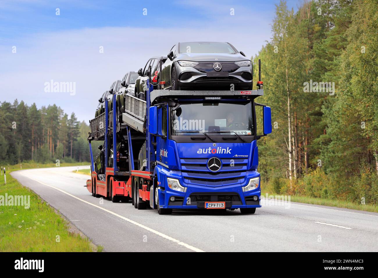 Blauer Mercedes-Benz Actros Fahrzeugträger Truck Autolink transportiert neue Mercedes-Benz Autos auf der Autobahn 25. Raasepori, Finnland. September 2023. Stockfoto