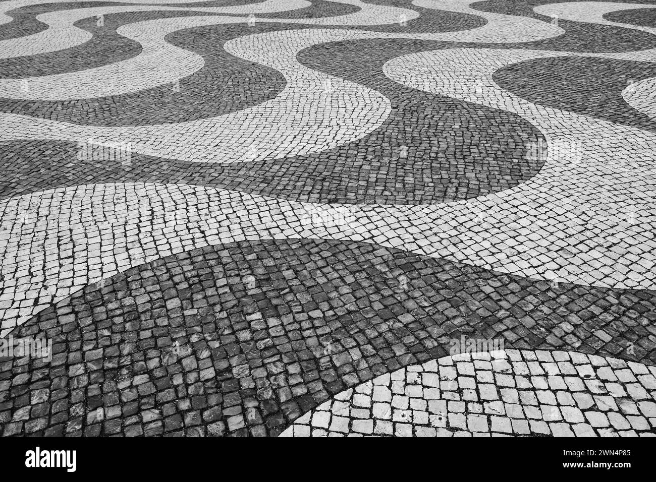 Typisch portugiesisches Mosaik-Pflastersteinpflaster in Lissabon, Portugal, schwarz-weiß. Stockfoto
