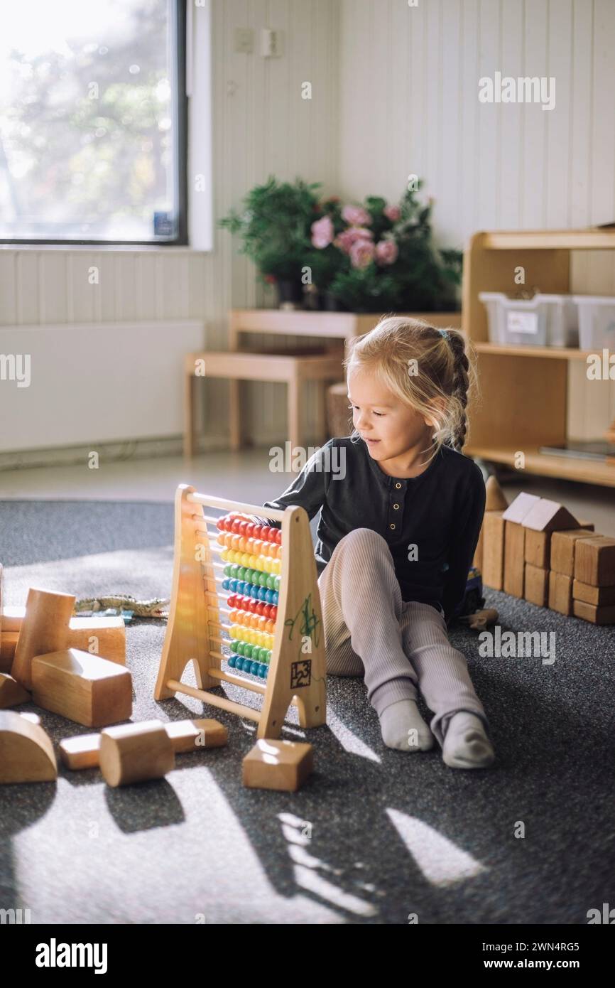 Mädchen lernt durch Abakus zählen, während sie im Klassenzimmer im Kindergarten sitzt Stockfoto