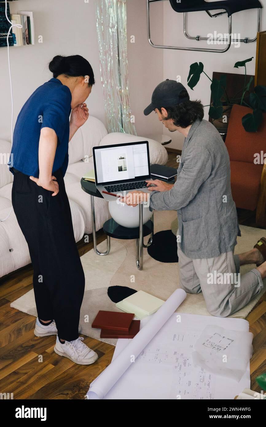 Multirassische Architekten diskutieren über Laptop per Blueprint im Heimbüro Stockfoto