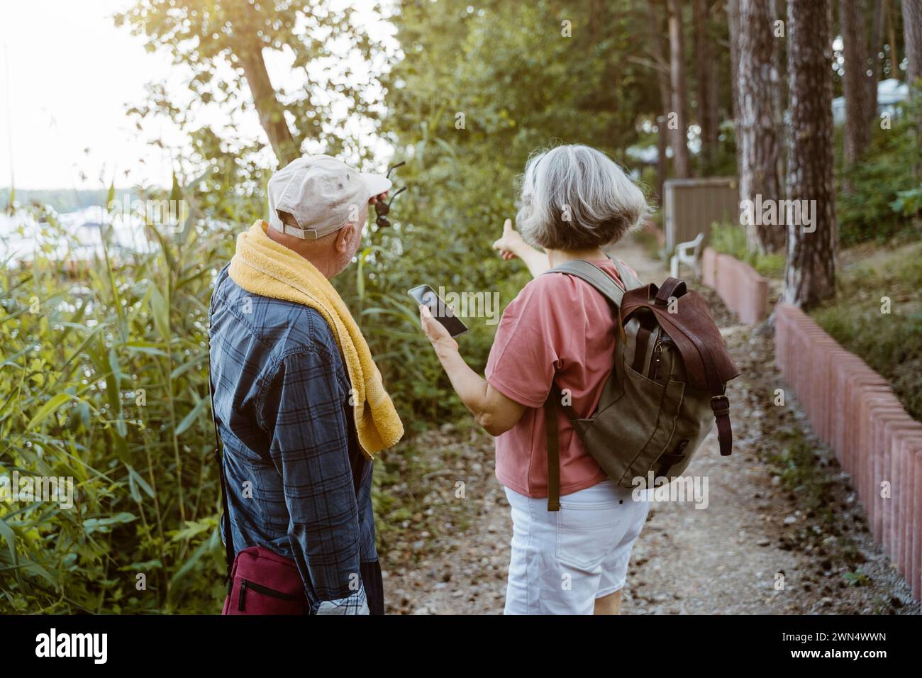 Seniorenpaar mit Smartphone, das beim Wandern im Wald zeigt Stockfoto