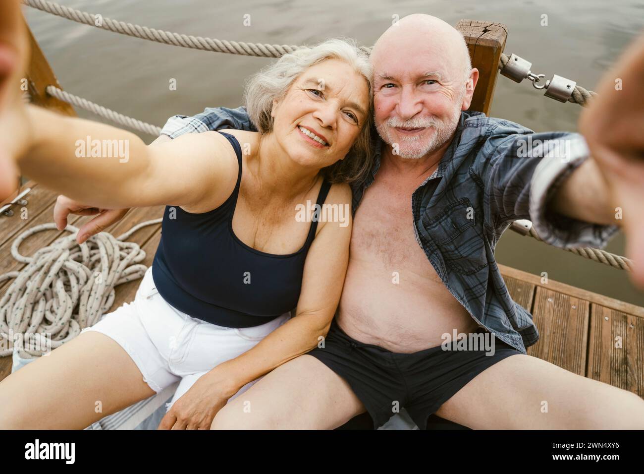 Glückliches Seniorenpaar, das Selfie macht, während es auf dem Hausboot sitzt Stockfoto