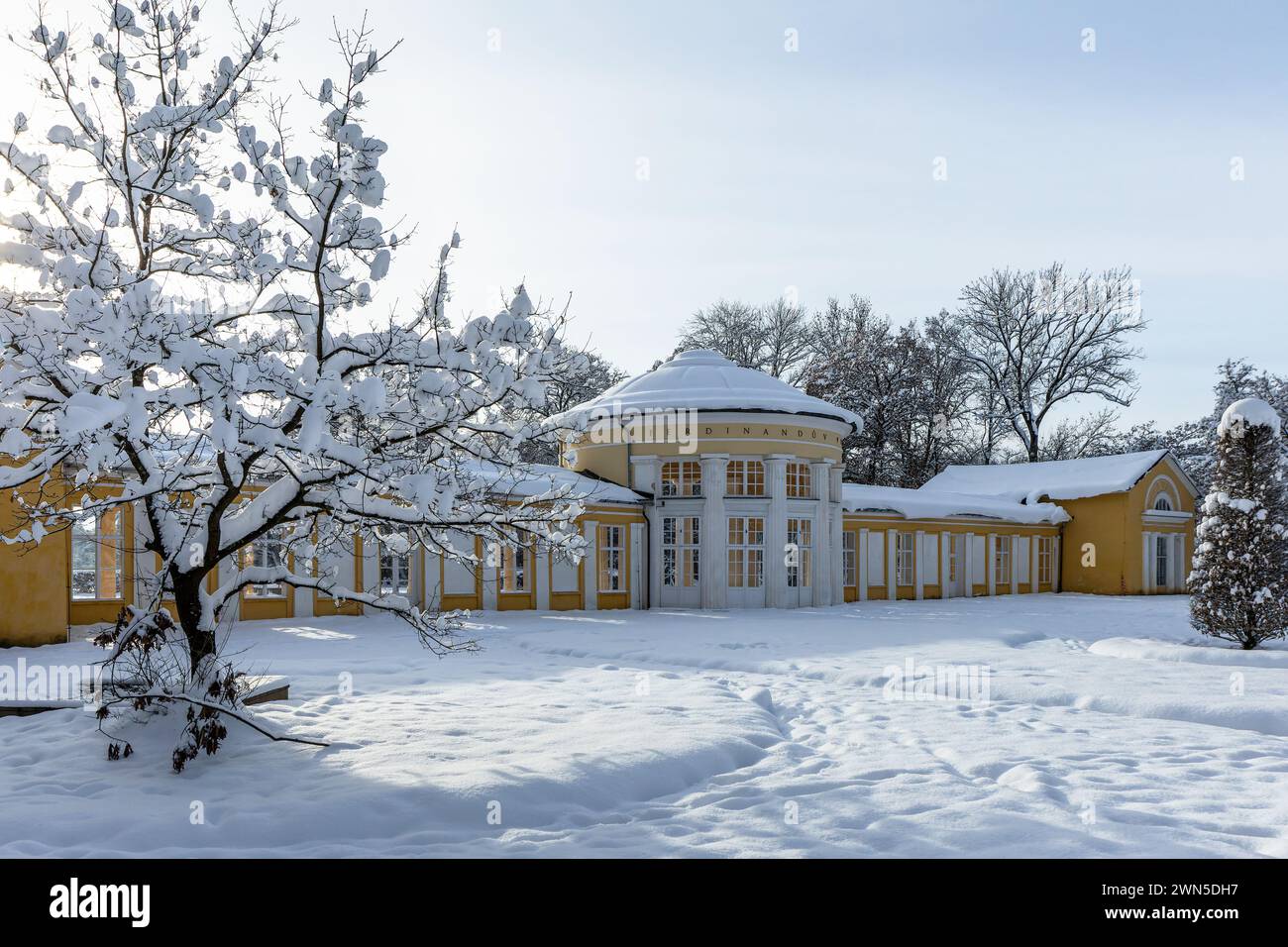 Marienbad, Tschechische Republik - 4. Dezember 2023: Gelb-weißes Gebäude des Ferdinand-Frühlingspavillons im Winter und schneebedeckte Bäume. Stockfoto